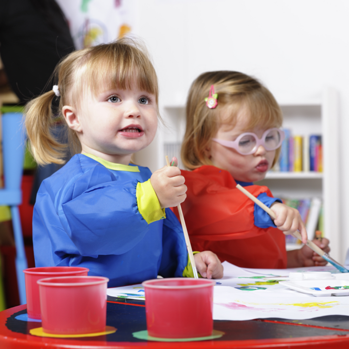 Two toddler paint in a preschool classroom.